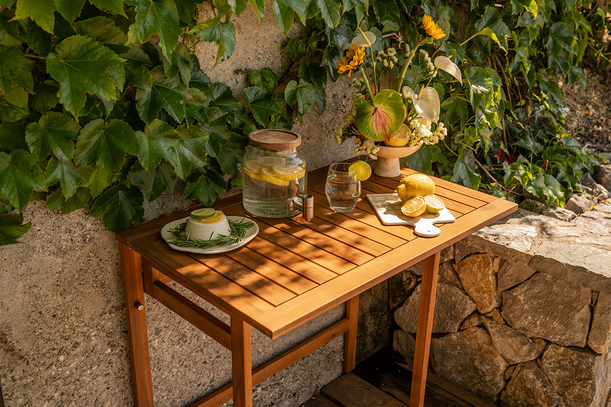 Tavolo da balcone pieghevole in legno massiccio con decorazioni, vista dall'alto, circondato da piante.