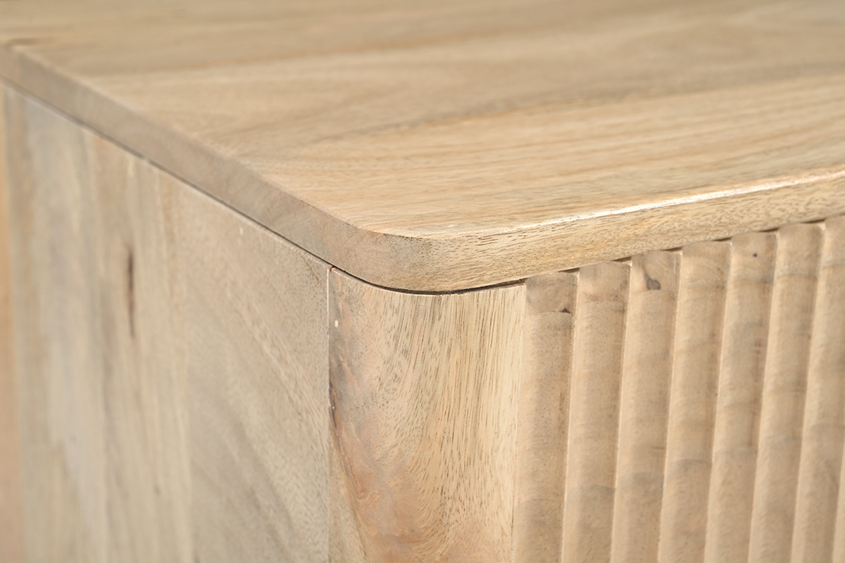 Dettaglio dell'angolo di un comodino in legno chiaro di mango, che mostra la finitura e le linee.