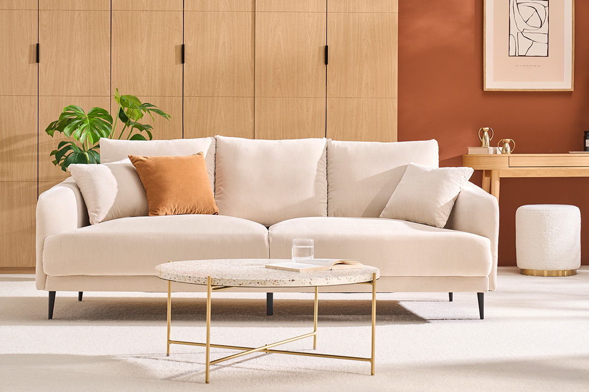 Tavolino basso rotondo in terrazzo e metallo, vista frontale, con divano e arredamento in un soggiorno moderno.