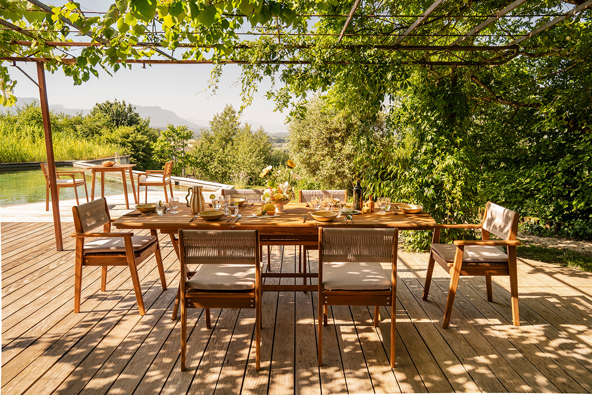 Tavolo da giardino allungabile CANOPEE in legno massello, vista frontale con sedie intorno, all'aperto