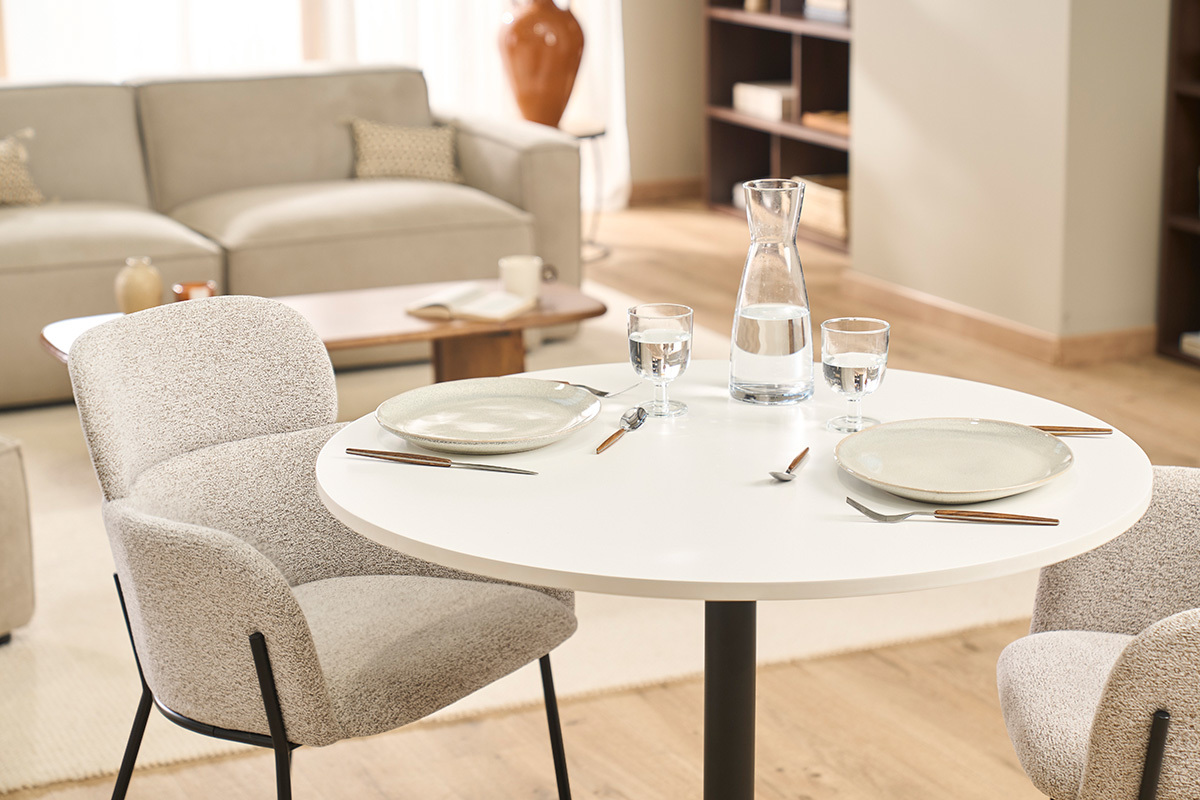 Tavolo da pranzo rotondo bianco e metallo nero CALISTA con stoviglie e caraffa, vista dall'alto.