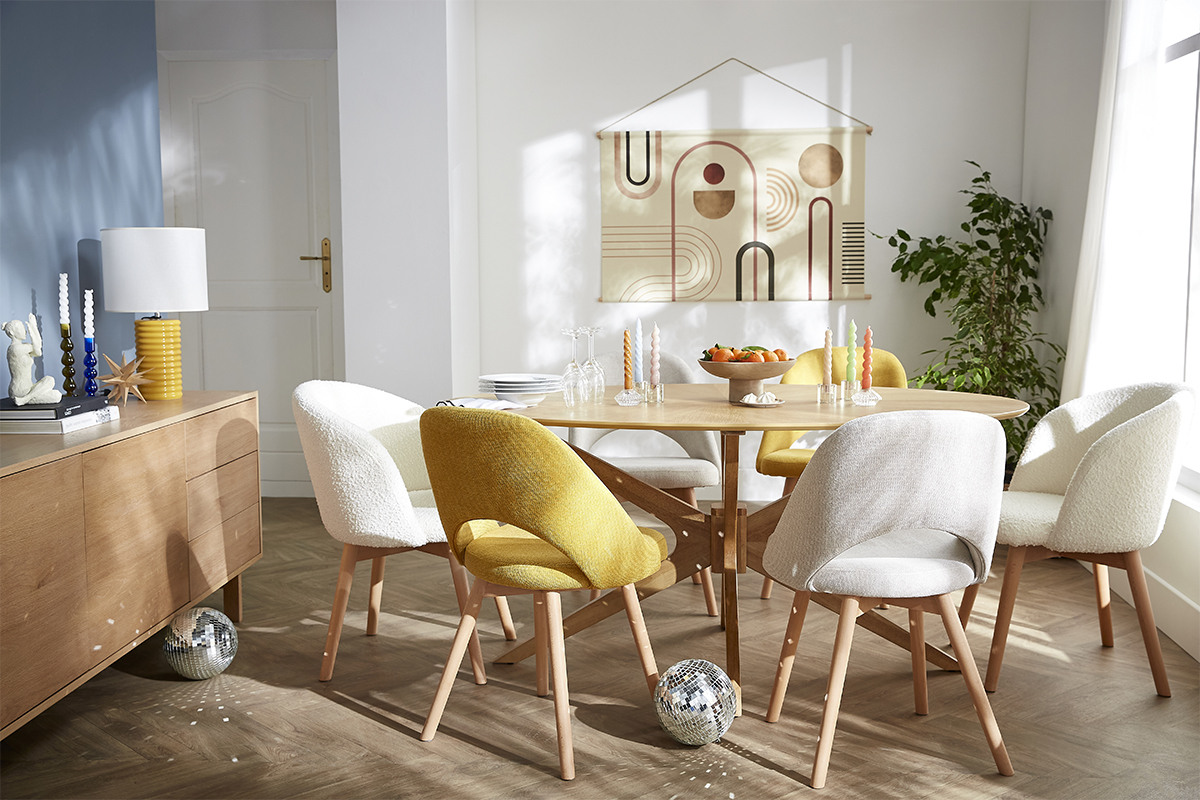 Tavolo da pranzo ovale in noce con sedie colorate in una sala da pranzo luminosa.