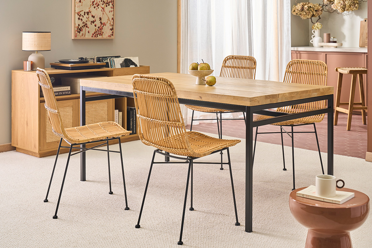 Tavolo da pranzo in legno e metallo con sedie in rattan in una sala da pranzo.