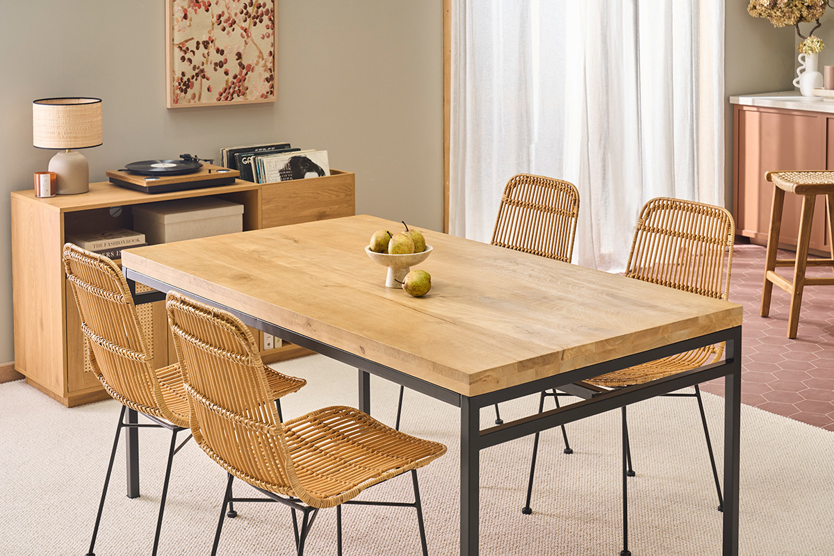 Tavolo da pranzo industriale in legno e metallo con sedie in rattan, vista angolare.