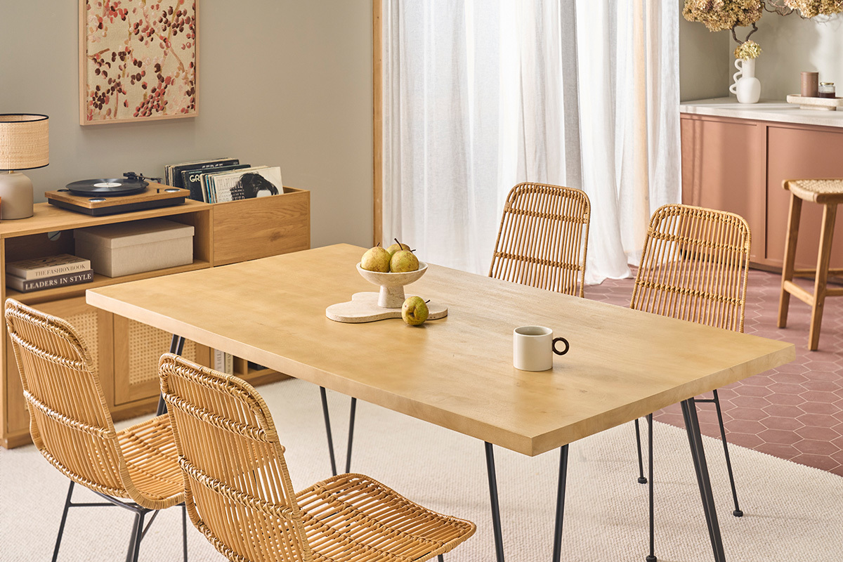 Tavolo in legno chiaro con 4 sedie in rattan e gambe in metallo, vista angolare.