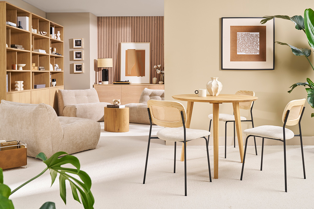 Tavolo da pranzo rotondo in legno chiaro con quattro sedie, vista d'insieme di un soggiorno moderno.