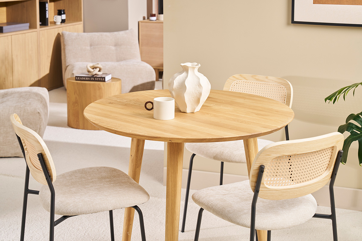 Tavolo rotondo in legno chiaro con sedie, vista d'insieme della sala da pranzo.