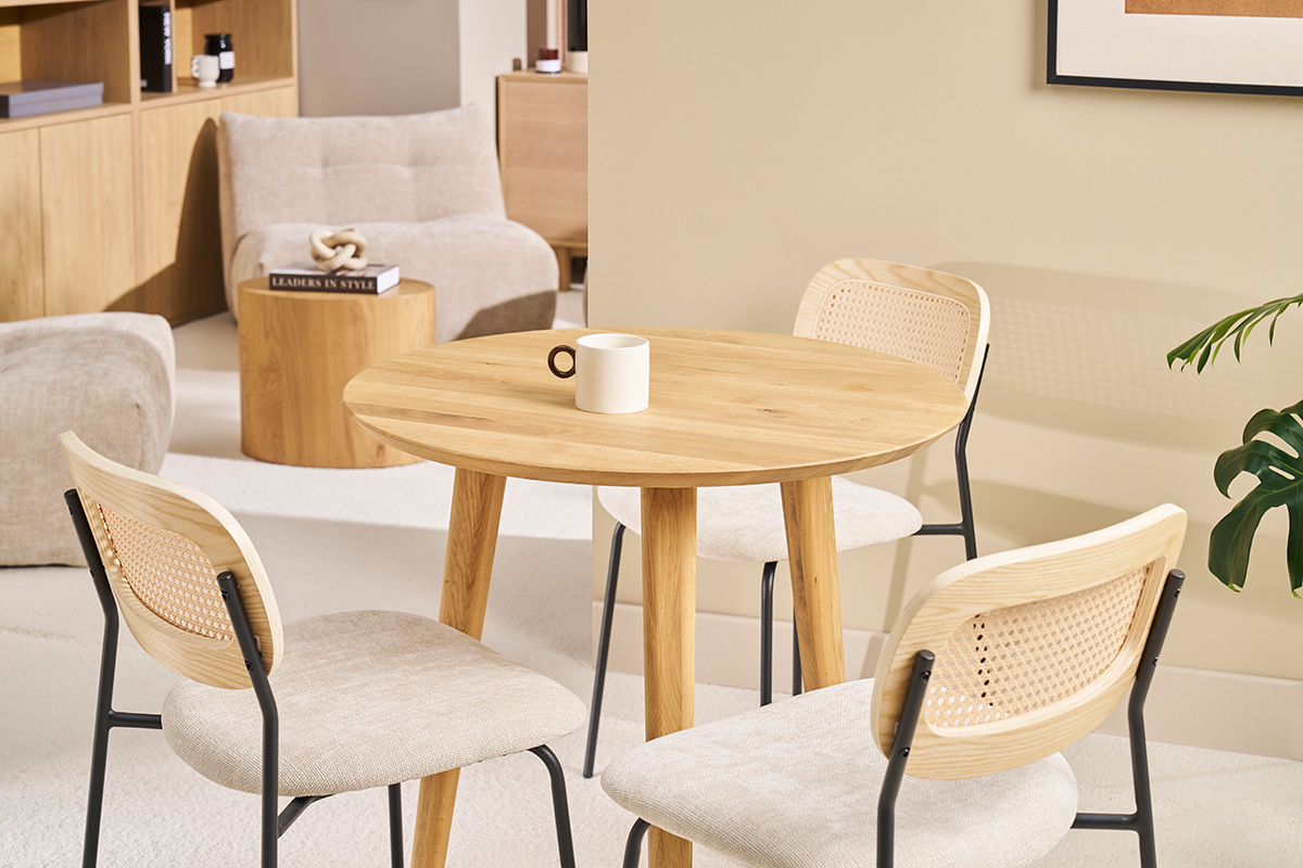 Tavolo rotondo in legno chiaro con sedie, vista d'insieme in un interno moderno.