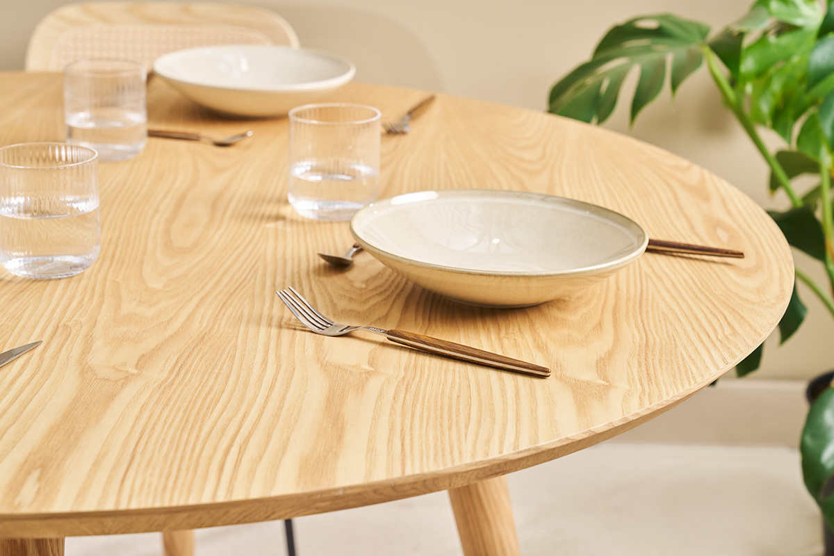 Tavolo rotondo in rovere chiaro D120 cm con stoviglie e posate, vista dall'alto.