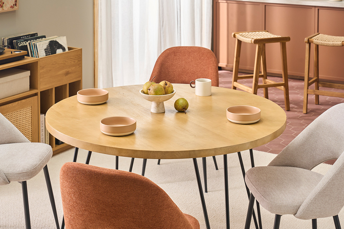 Tavolo rotondo in mango con piatti, sedie e decorazioni da cucina.